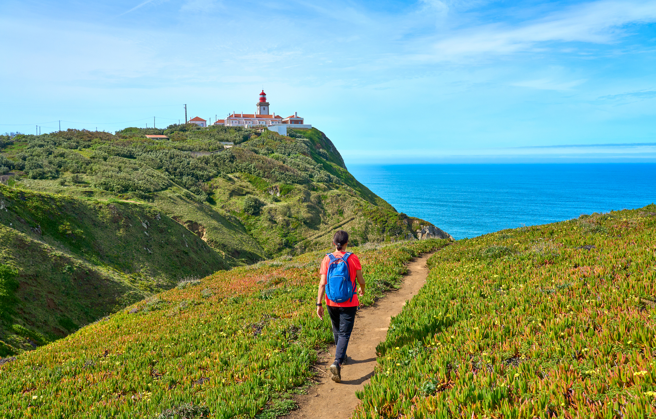 Woman walking on a coastal boardwalk at golden hour, Portugal